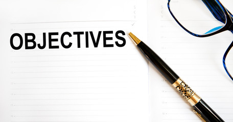 The Objectives inscription on the tablet with a fixed sheet of paper, next to glasses and a pen.