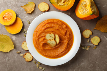 Composition with plate of pumpkin puree with croutons on gray background, top view