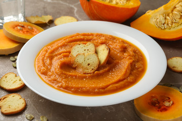 Plate of pumpkin puree with croutons on gray background, close up