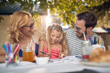 Happy family sitting at garden with their  daughter and spending time together.