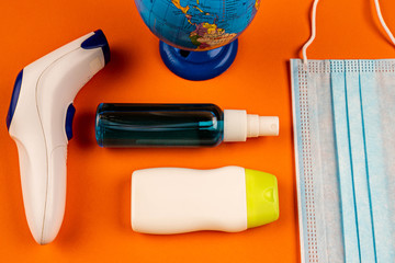 World globe with medical accessories on orange background. Top view of small globe next to hand...