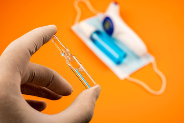 Close-up view of hand with protective gloves holding ampoule. Human hand with gloves holding...