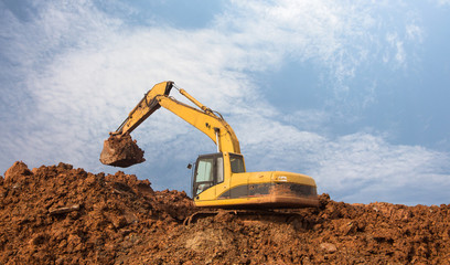 Fototapeta na wymiar Large yellow excavator digging on the mound