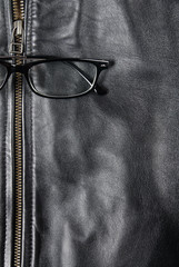 Detail of classic old black leather jacket with eyeglasses