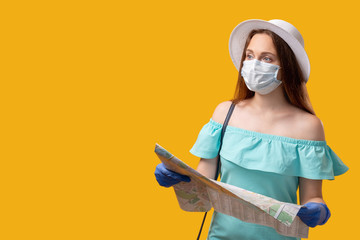 Pandemic tourism. Travel agency. Curious woman in protective face mask gloves searching location with map isolated on yellow looking at empty space. COVID-19 quarantine safety measures. New normal.