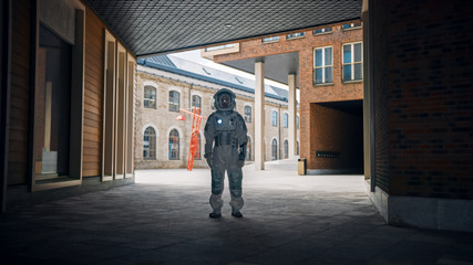 Low Angle Shot of a Confident Handsome Astronaut is Stands in a Neighbourhood with Modern Scandinavian Buildings. Man in Futuristic Suit with Technological Panel on His Hand.