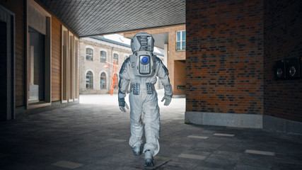Low Angle Shot of a Confident Handsome Astronaut from the Back in a Neighbourhood with Modern Scandinavian Buildings. Man in Futuristic Suit with Technological Panel on His Hand. © Gorodenkoff