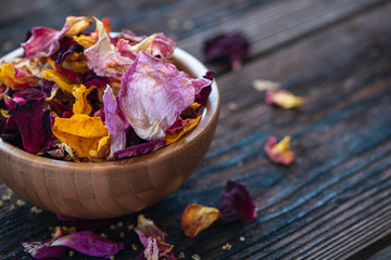 Schälchen mit Rosenblütenblättern auf Holzuntergrund- Konzept Naturkosmetik