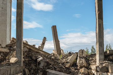 Concrete fragments of a destroyed building against the blue sky. Background