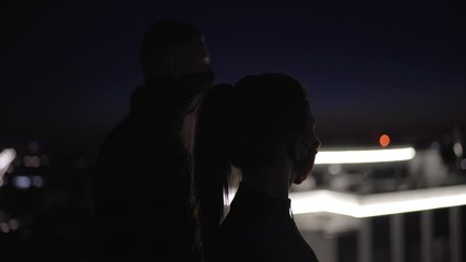 Mysterious man and woman in face masks looking at night city, guarding security