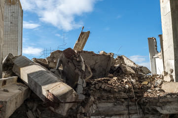 Concrete fragments of a destroyed building against the blue sky. Background