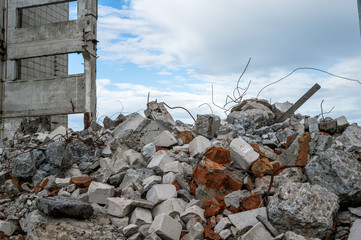 Concrete debris with rebar against the background of a destroyed building and a gray sky....
