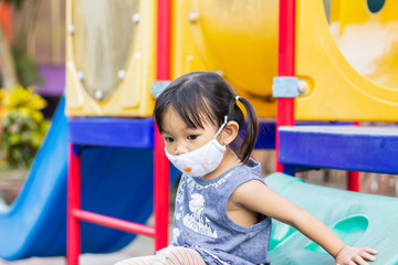 Fototapeta na wymiar Portrait image of 2-3 yeas old baby. Happy Asian child girl smiling and wearing fabric mask,​ She playing with slider bar toy at the playground, social​ Distance,​ Learning and active of kids concept.
