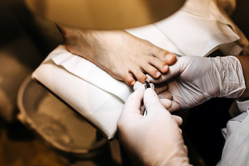 Woman at a pedicure procedure at a beauty salon. Close-up of a specialist cutting cuticles