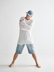 Cool stylish young guy breakdancer in cap barefoot standing in studio isolated on white background. Dance school poster