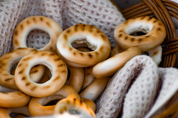 Baked bagels, crunchy dried products, sweet flour dessert with vanilla flavor in a wicker basket with a waffle towel at a picnic
