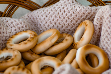 Baked bagels, crunchy dried products, sweet flour dessert with vanilla flavor in a wicker basket with a waffle towel at a picnic