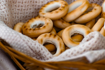 Baked bagels, crunchy dried products, sweet flour dessert with vanilla flavor in a wicker basket with a waffle towel at a picnic