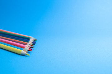 The row of color pencils on the blue background 