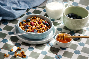 breakfast with granola and nuts and blueberries, honey and milk, mediterranean ceramics