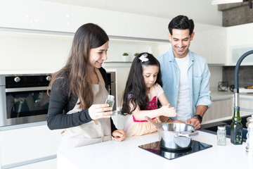 Parents Looking At Daughter Learning To Cook