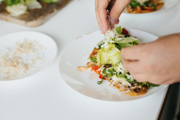 Hands putting parmesan slices on homemade pizza on plate on modern kitchen.Slice of delicious pizza with mushrooms, tomato, arugula and cheese. Home cooking concept