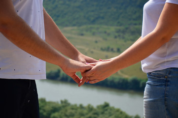 male and female hands on hold each other against nature background