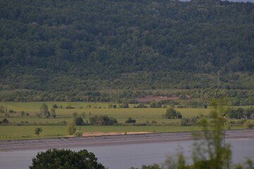 spring landscape with forest near the lake at sunset. cultivated fields