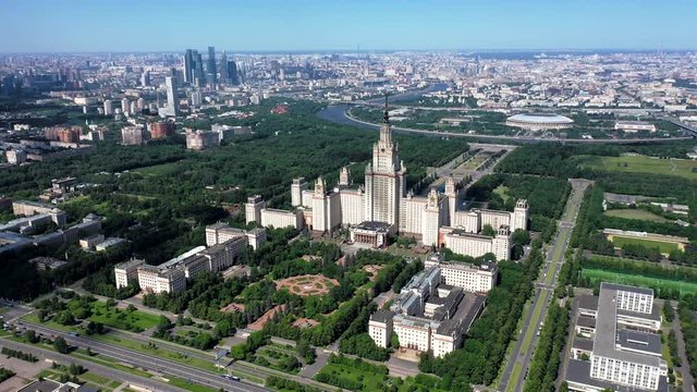 Moscow State University top overhead from drone with slow landing motion on point of interest. Close up view in the end. Megapolis and skyline on background.