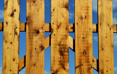 Fototapeta premium Ocher wooden fence. Clear summer sky. Solar lighting