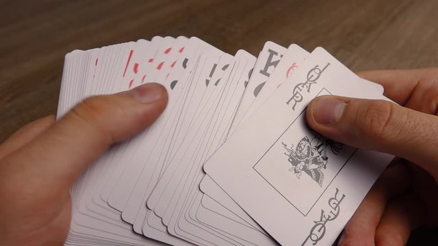 man shuffles the deck of cards in his hands