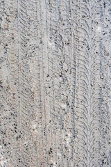 Tire tracks on a snowy road covered with sand and granite chips