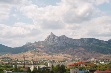 city in the mountains with white clouds and green hills