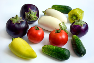 Juicy ripe tomatoes, cucumbers, peppers, purple and white eggplants on a white background.