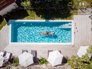 two person swim in the pool at the hotel. View from above, couple men and women in swimming pool of...