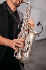 A musician at the event  plays the saxophone. Сlose-up of hands and tools