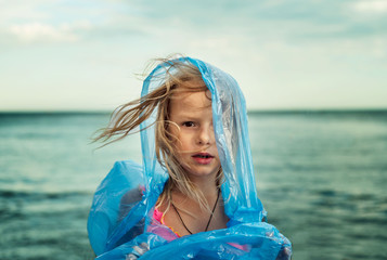 Little girl wearing raincoat on windy day at the beach