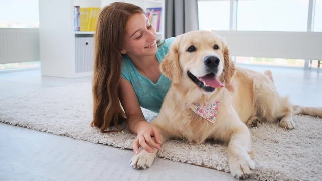 Girls with dog lying on a floor indoors, golden retriever breed