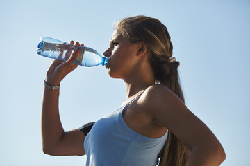Close up portrait of an attractive young woman drinking water from bottle.