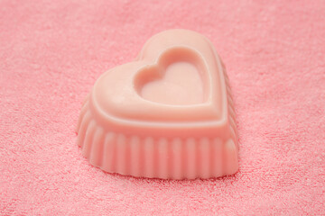 Heart-shaped pink handmade soapon pink background, close up	