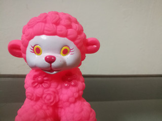 Closeup shot of a sheep doll with red color and red color ears and flowers on it.