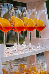 Outdoor catering banquet in summer. Empty wine glasses with orange slice for cocktails stand in a row at a banquet
