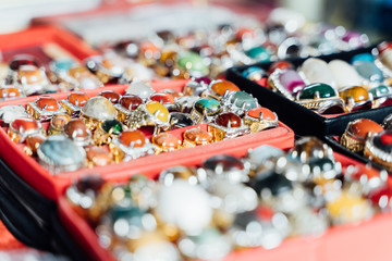 Different jewels with stones in boxes at a market stop