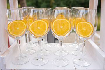 Outdoor catering banquet in summer. Empty wine glasses with orange slice for cocktails stand in a row at a banquet