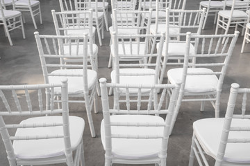 Empty white chairs for guests at a banquet or wedding on an outdoor summer area are in a row