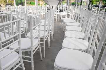Empty white chairs for guests at a banquet or wedding on an outdoor summer area are in a row