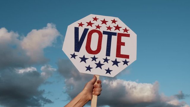 VOTE word on white board hands raise with American flag against blue sky white clouds  background. Presidential and parliamentary elections. Call for voting, for democracy. Electoral Voting. Politics