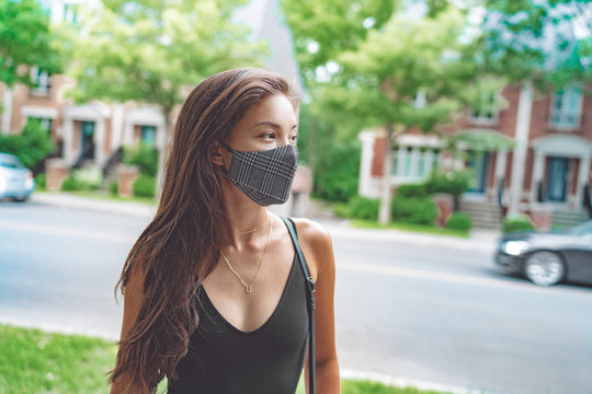 Asian woman walking in city street wearing face mask for COVID 19 prevention. Happy young student with fashion pattern cloth mouth covering outside. Corona virus concept.