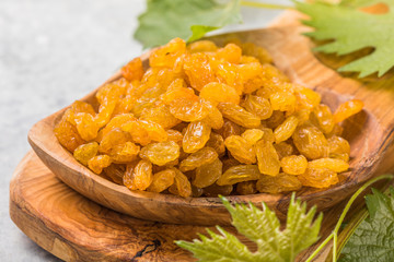 Golden raisins or sultana in bowl on stone background. Dried fruit, healthy snack food