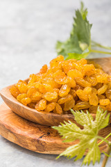 Golden raisins or sultana in bowl on stone background. Dried fruit, healthy snack food